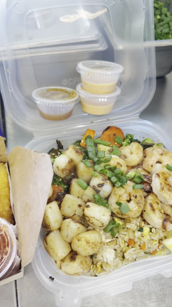 Shrimp and scallop plate over fried rice with a lemon wedge, packed for pickup