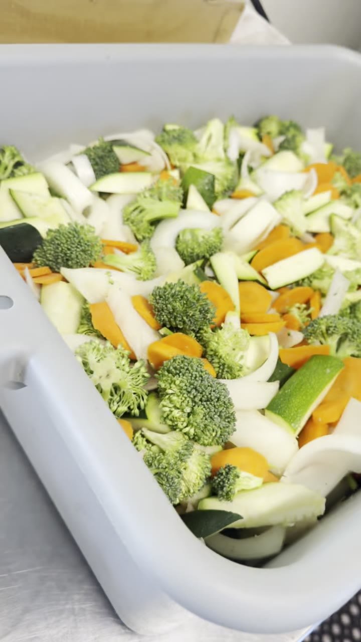 A bin of fresh cut broccoli, carrot, onion and zucchini ready for the griddle