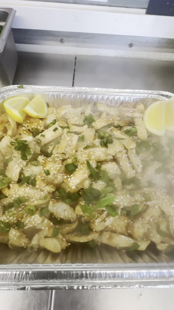 A tray of hibachi chicken with lemon wedges
